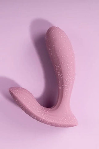 Svakom Erica, en trosvibrator med ergonomisk design, har en texturerad silikonyta som inbjuder till utforskande mot en rosa bakgrund.