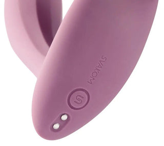 En närbild av Svakom Erica, en lila bärbar enhet, framhäver dess ergonomiska design med en knapp och varumärkeslogotyp, som erbjuder appkontrollerad funktionalitet för sömlös kontroll.