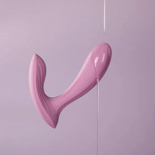 Svakom Erica, en rosa abstrakt skulptur med en svängd, modern design, står elegant mot en ljuslila bakgrund.